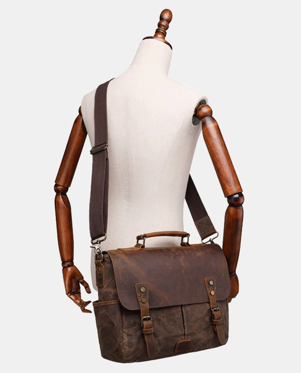 Model carrying brown canvas messenger bag with leather flap